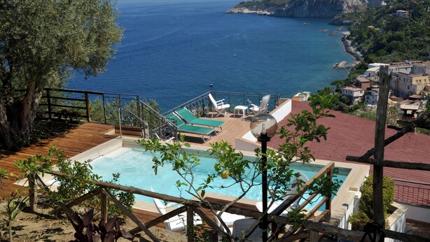 A pool with a view of the sea, a wooden deck, and a staircase leading to a terrace. - The Phoenix White house (Massa Lubrense)