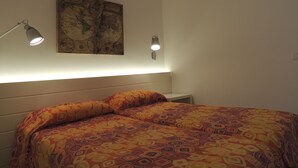 A bedroom with a bed, two bedside lamps, and a world map on the wall. - The Phoenix White house (Massa Lubrense)