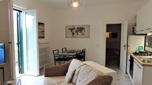 A compact living space with a sofa, a dining table, and a kitchen area. - The Phoenix White house (Massa Lubrense)