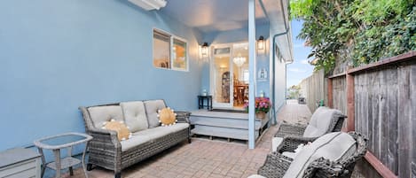 Une terrasse avec des meubles en osier, une petite table et une clôture en bois.