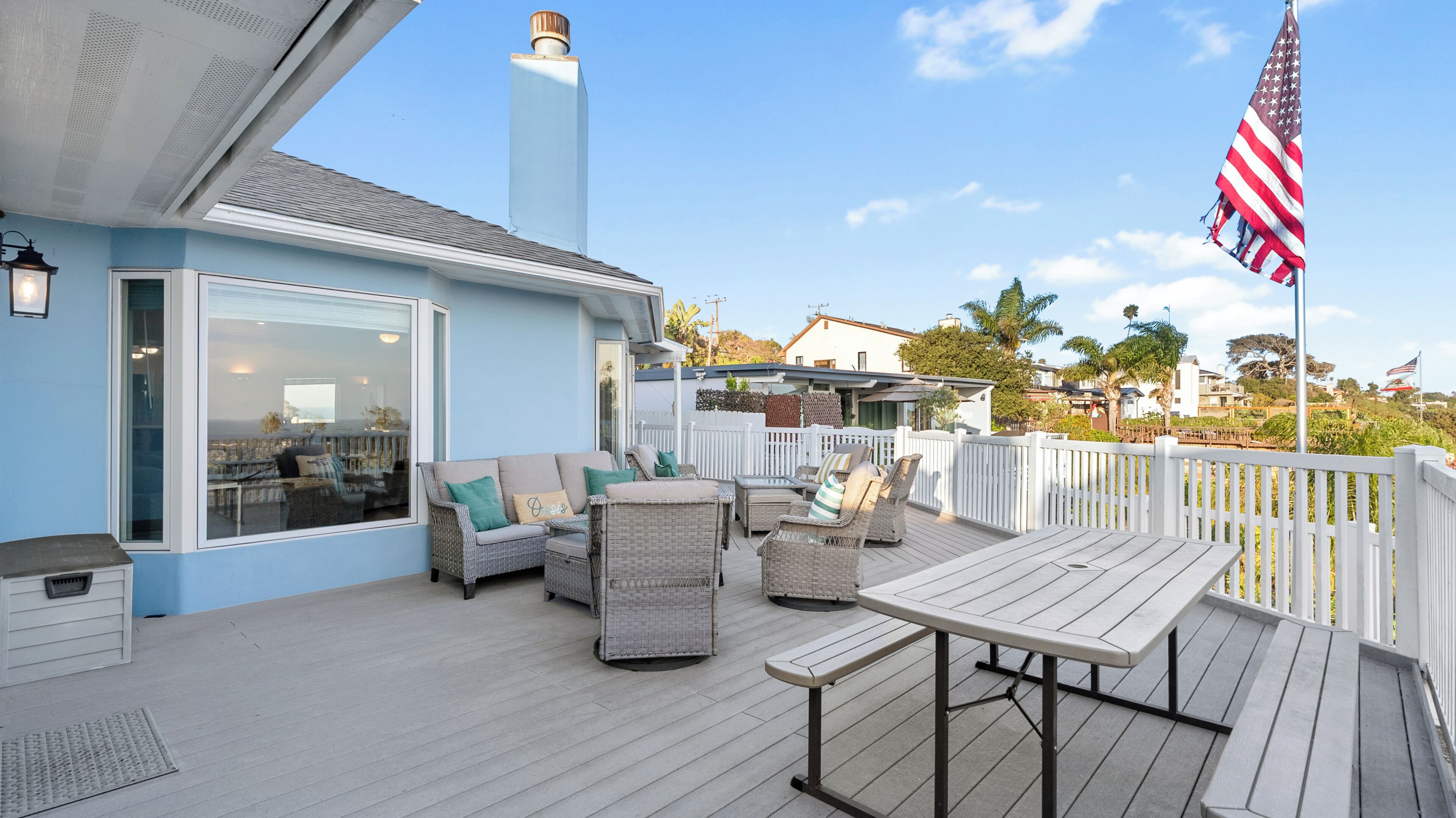 A deck with outdoor furniture, a flag, and a view of the neighborhood.