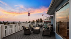 A deck with outdoor furniture, two American flags, and a view of the ocean at sunset. - Oceanview home walking distance to beach, pier & short drive to downtown Ventura (Ventura)
