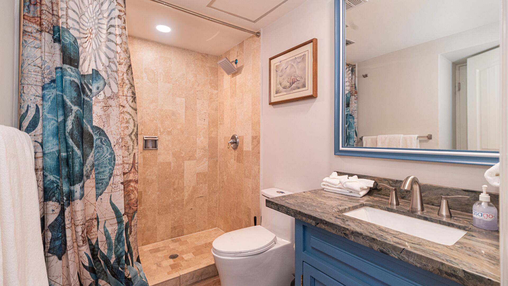 Une salle de bain équipée d’une douche, de toilettes, d’un lavabo et d’un grand miroir.