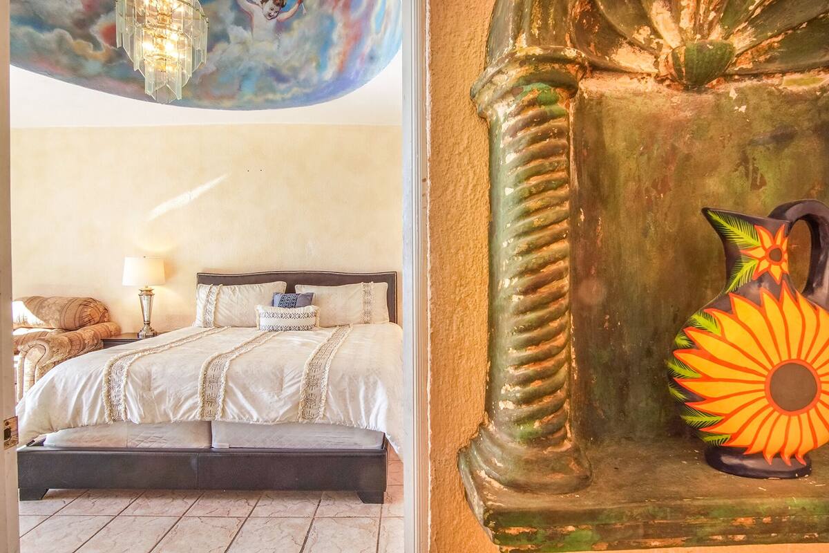 A bedroom with a bed, bedside table, lamp, and a decorative vase.