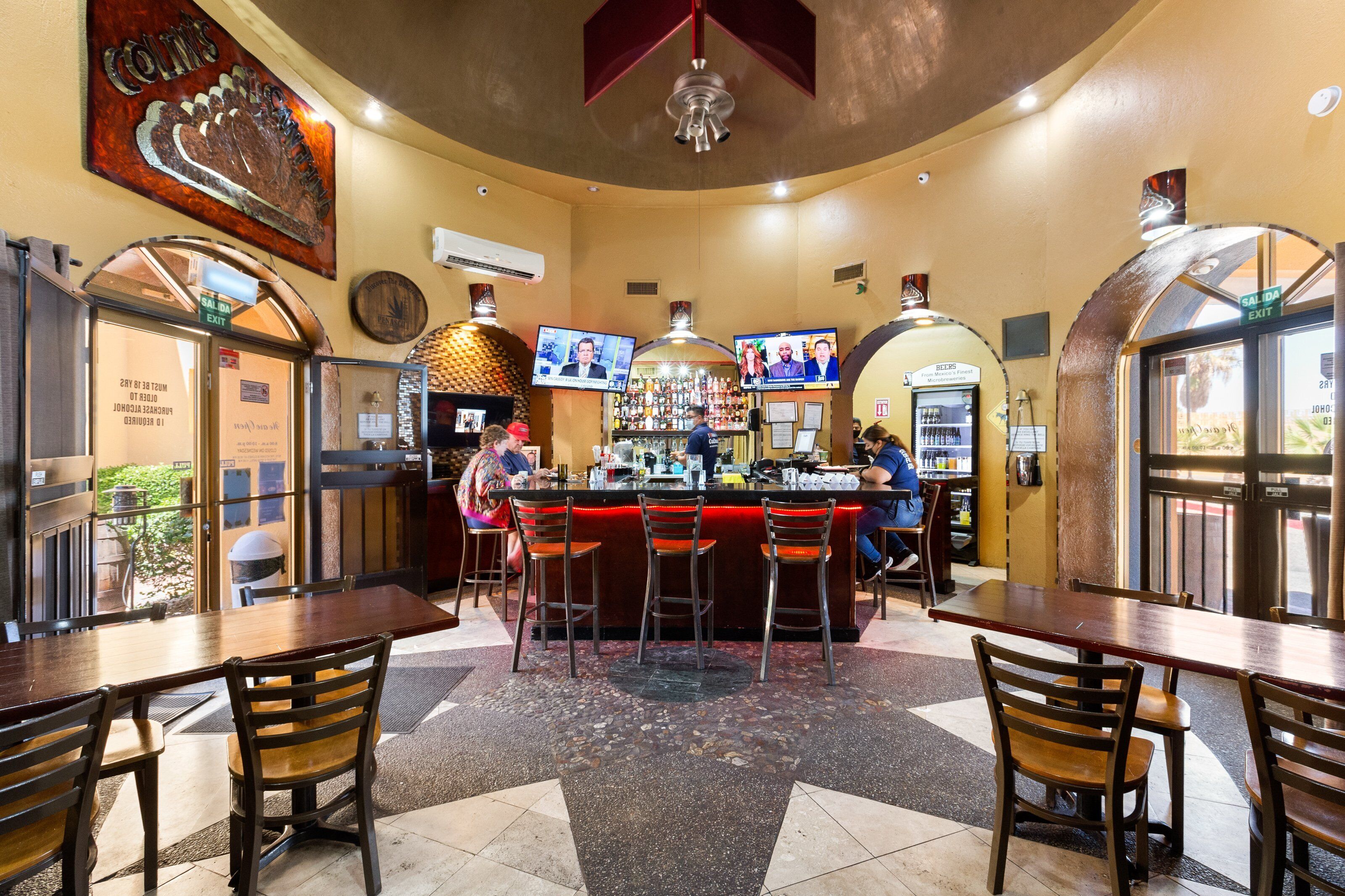 A bar area with stools, a counter, and a television screen.