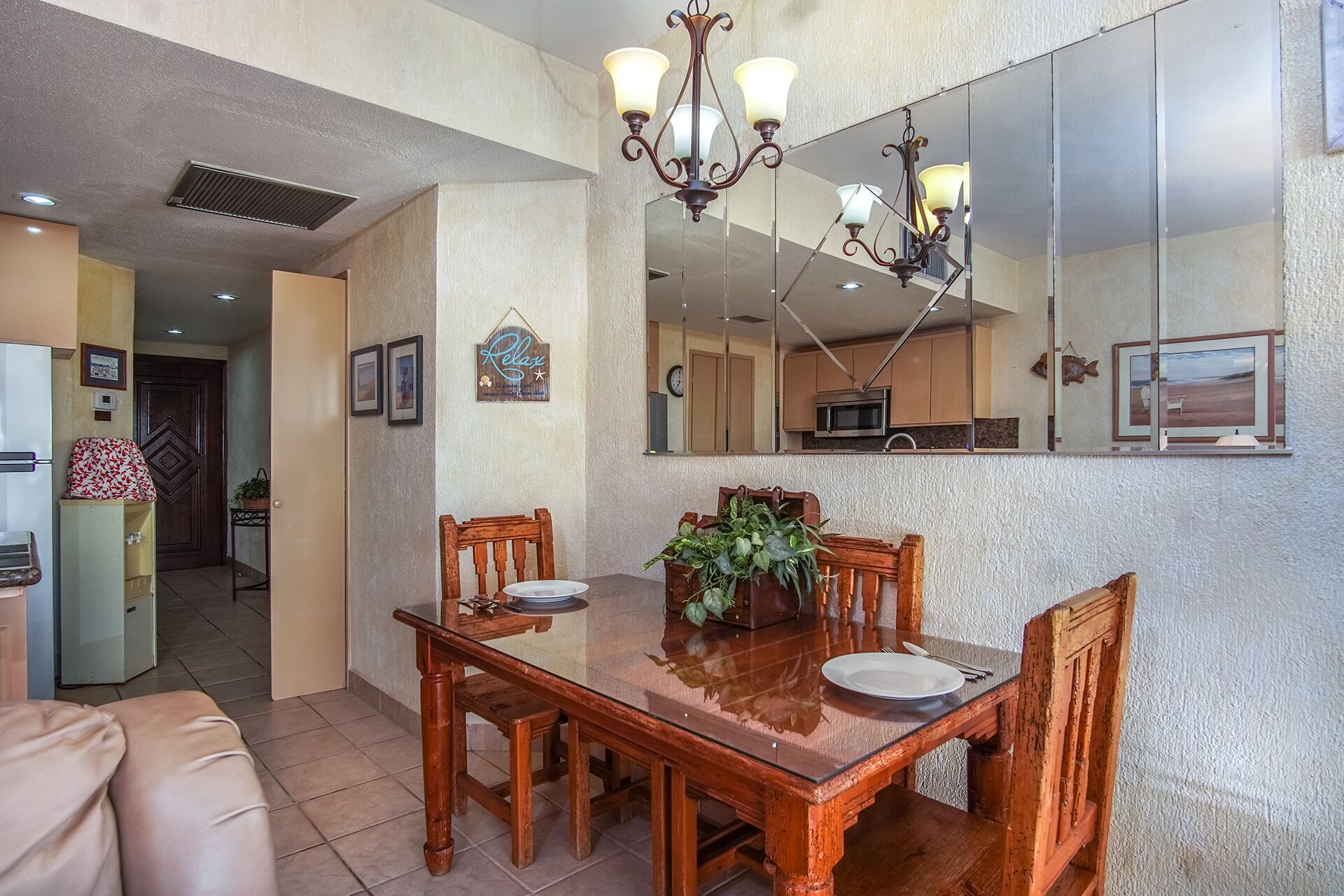Un comedor con mesa y sillas de madera, un candelabro y un espejo grande sobre la mesa.