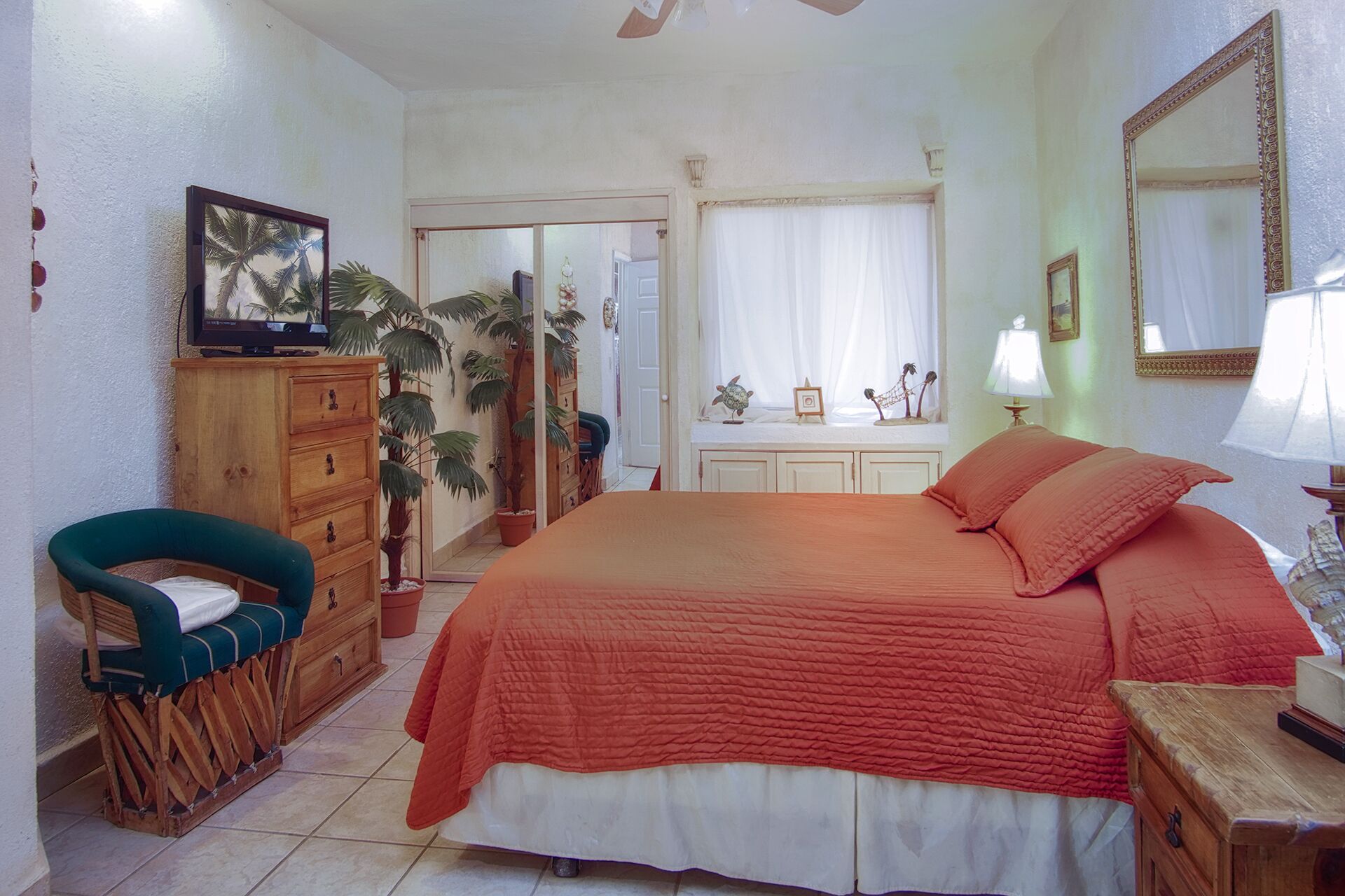 A bedroom with a large bed, wooden furniture, a television, and a window with curtains.