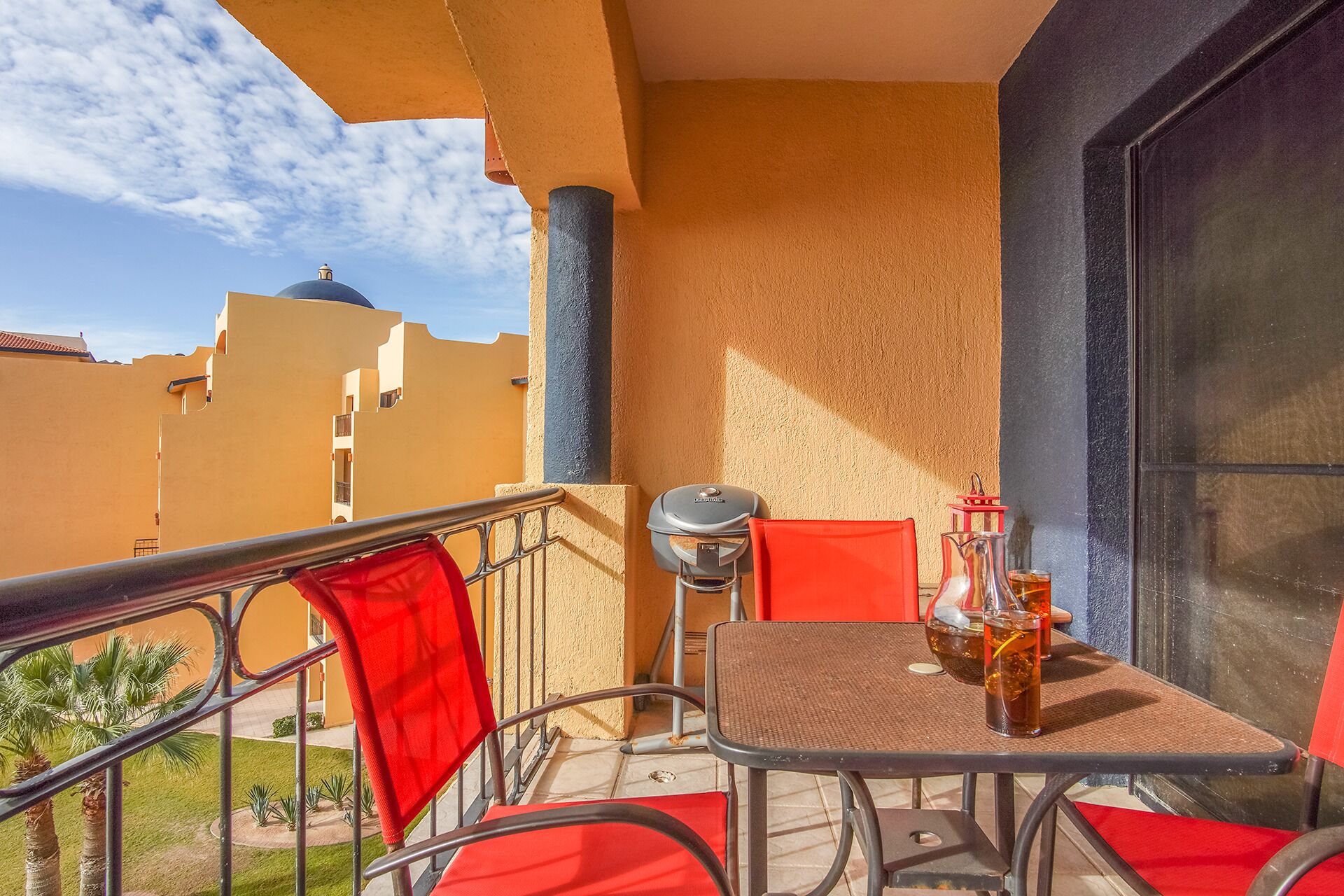 Un balcon avec une table, des chaises, un barbecue et une vue sur les immebles.
