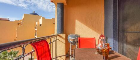 Un balcon avec une table, des chaises, un barbecue et une vue sur les immebles.