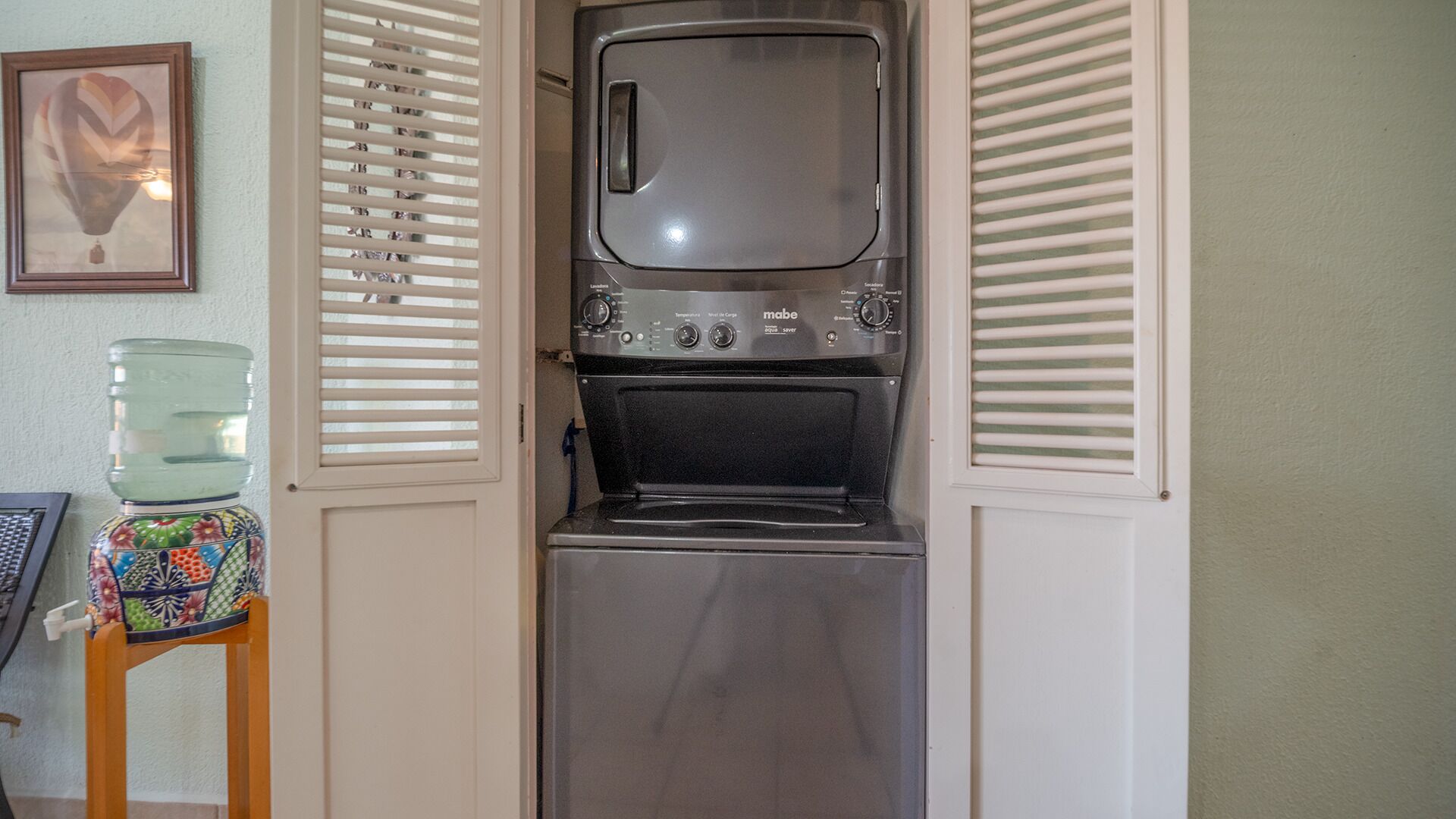 A compact kitchen with a built-in oven and microwave, a water dispenser, and a small sink.