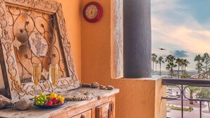 Un balcón con un mueble de madera decorativo, un reloj y vistas a una piscina y palmeras.