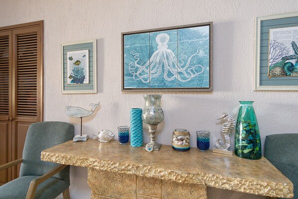 A room with a stone table displaying decorative items, framed artwork on the wall, and a wooden door with shutters. - Princesa De Penasco II (Puerto Peñasco)