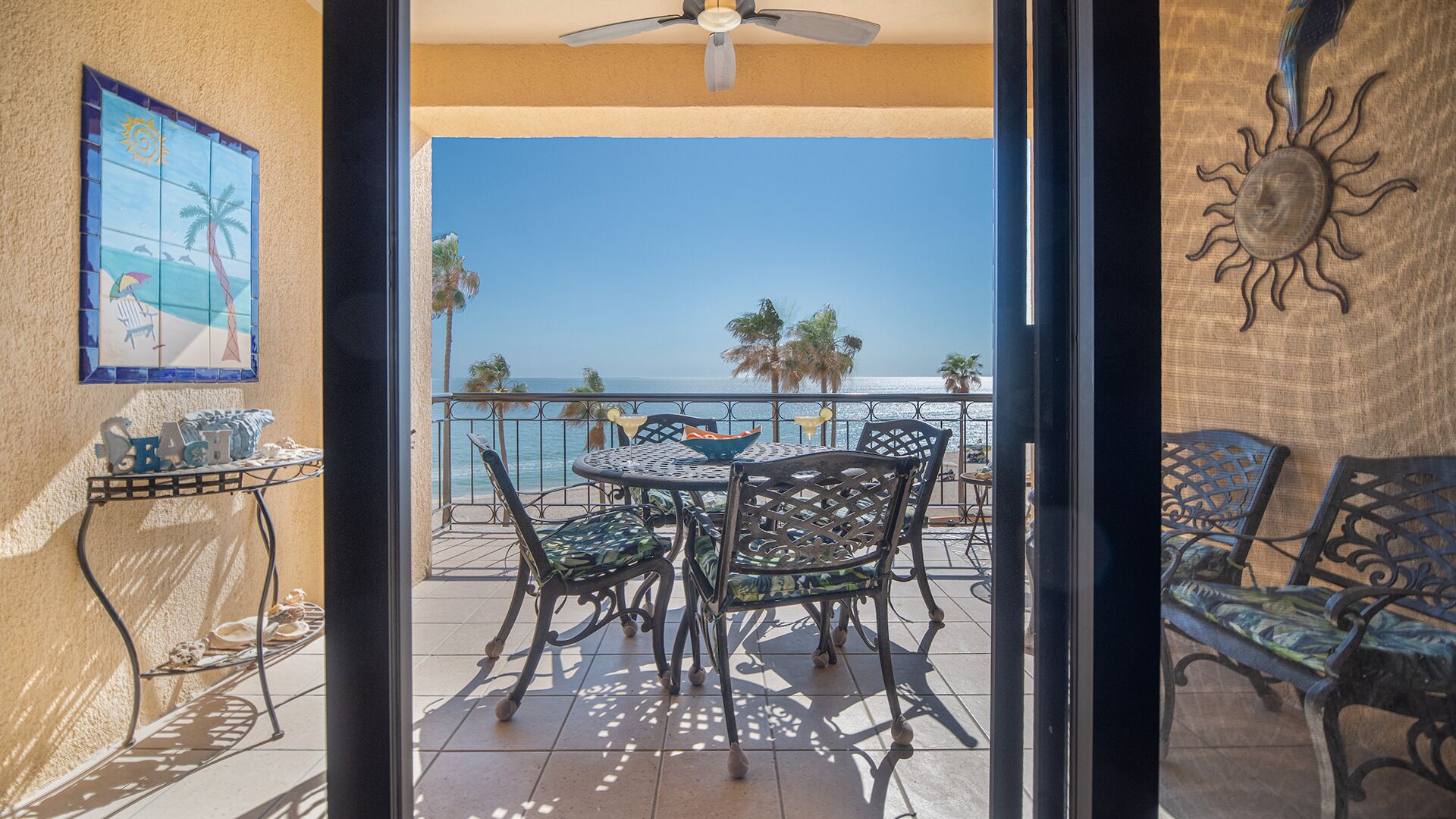Uma varanda com mesa e cadeiras, uma decoração solar e vista para o oceano.
