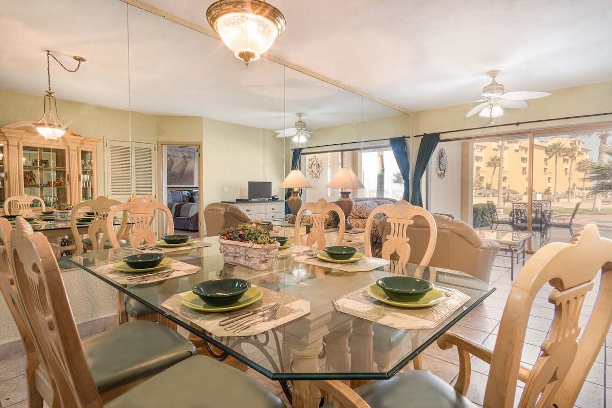 A dining area with a glass table, wooden chairs, and a chandelier.