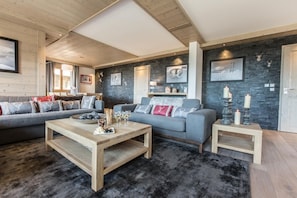A modern living room with a grey sofa, a wooden coffee table, and a stone accent wall.