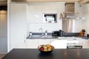 A modern kitchen with white cabinetry, a stainless steel sink, a built-in oven, and a coffee maker.