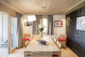 Ein Essbereich mit einem Holztisch, Stühlen, einem Blumenstrauß und einer Wand mit einem aufgehängten Hirschkopf und gerahmten Bildern.