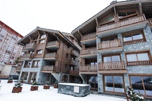 A multi-story hotel with balconies, stone facade, and snow-covered ground.