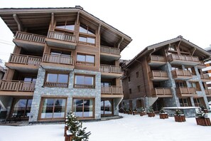 Ein mehrstöckiges Hotel mit Balkonen und großen Fenstern, umgeben von Schnee.