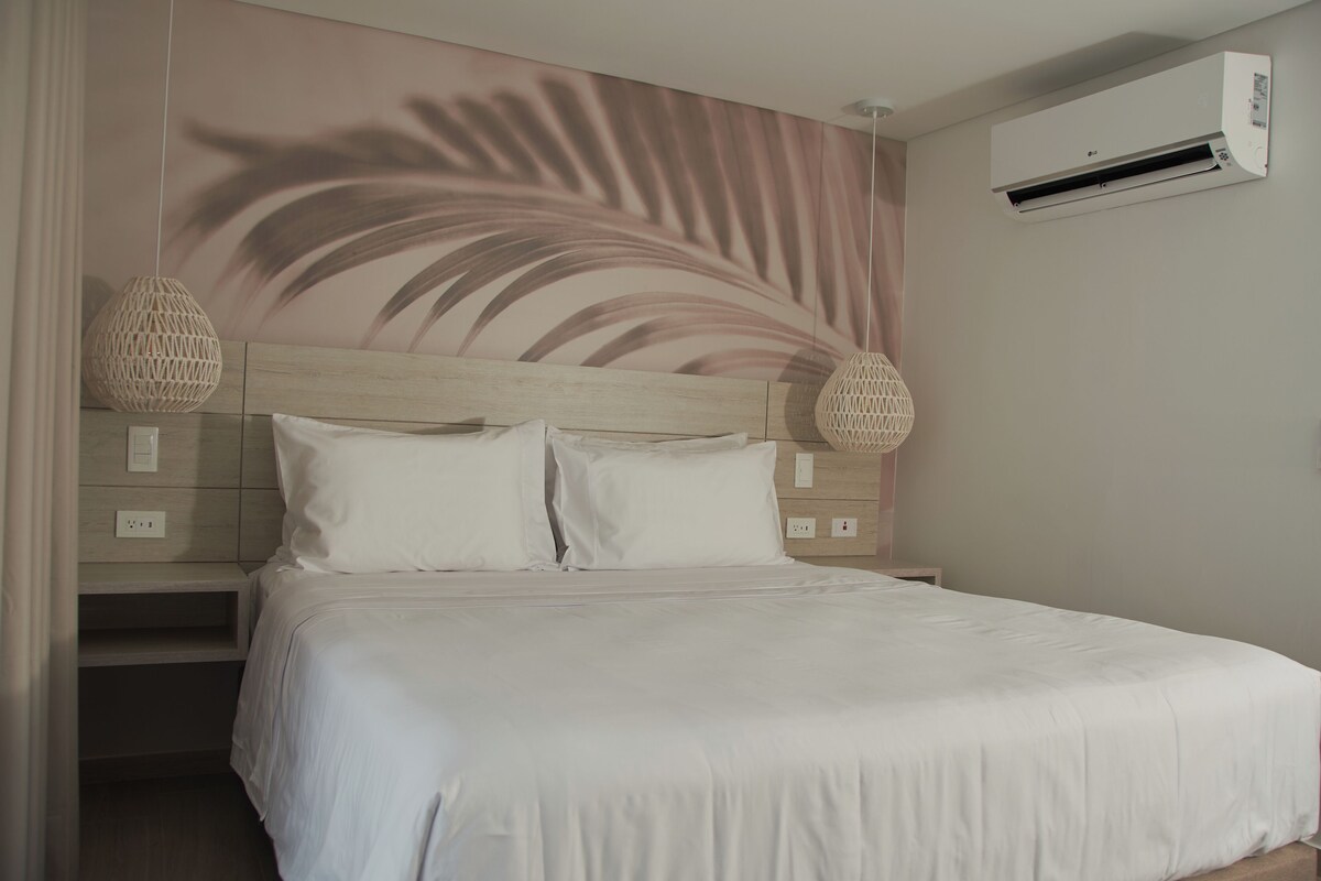 A bedroom with a bed, a wall-mounted air conditioner, and a wall with a palm leaf design.