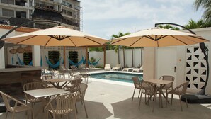 An outdoor pool area with lounge chairs and tables, surrounded by umbrellas. - Zafi Hotel (San Andrés)