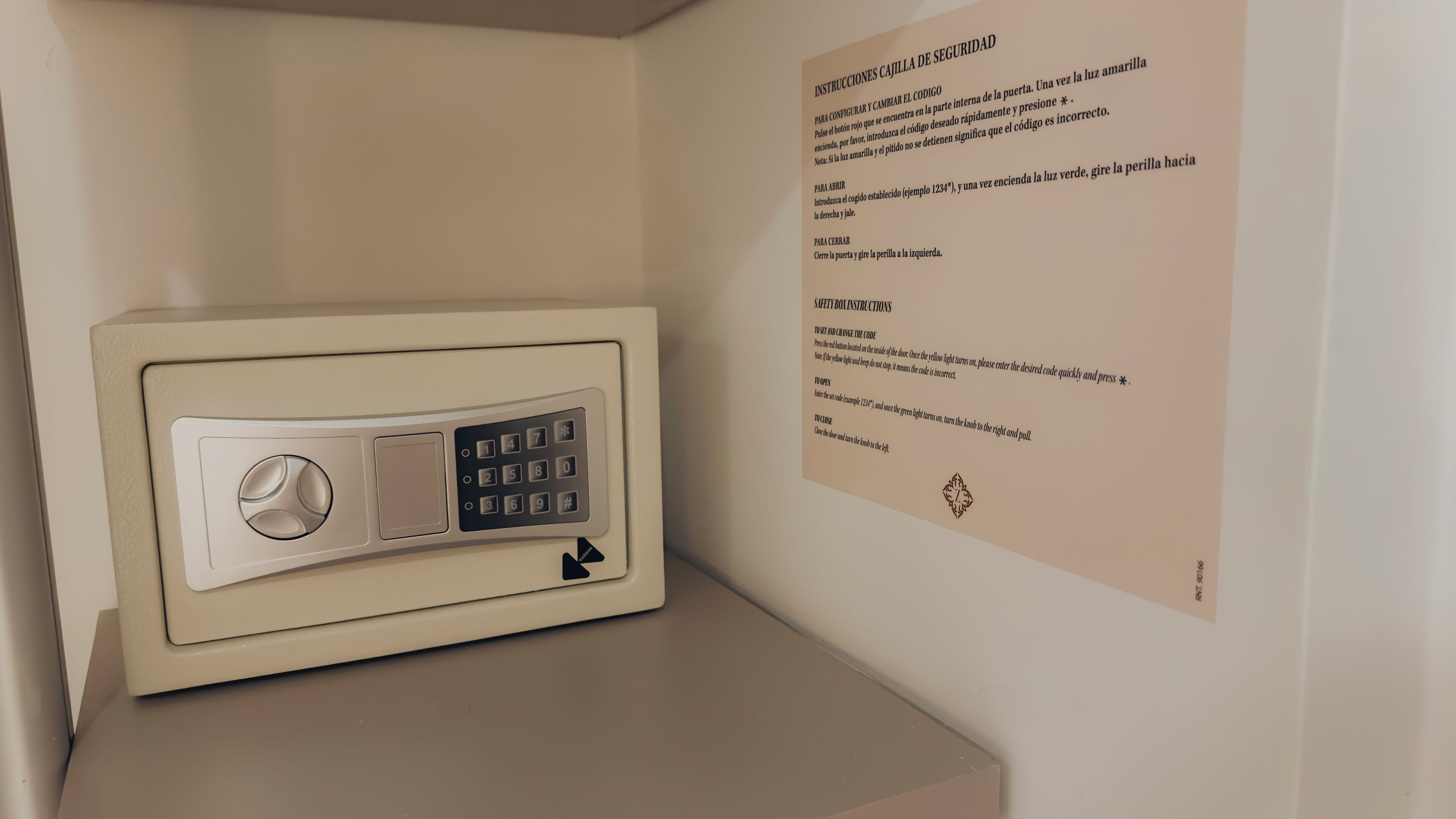 A safe with a keypad and a wall-mounted instruction manual detailing its use.