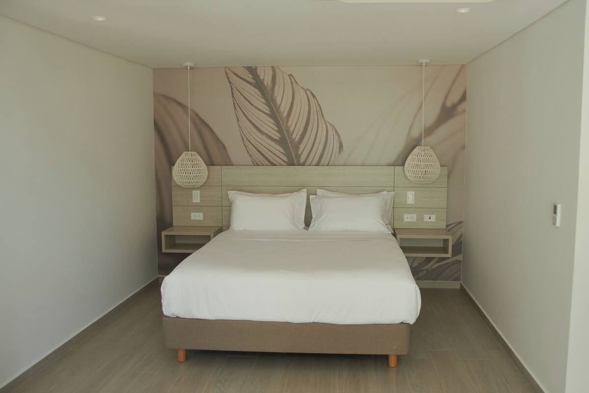 Un dormitorio moderno con una cama grande, cabecera de madera y dos mesitas de noche con lámparas.