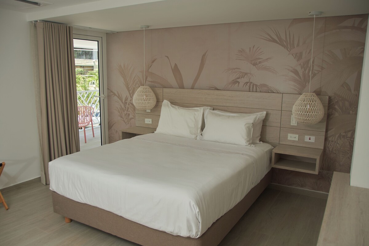 A bedroom with a large bed, a wooden headboard, and a wall with a tropical leaf pattern.