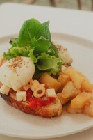 A plate with a poached egg, greens, and potato wedges.