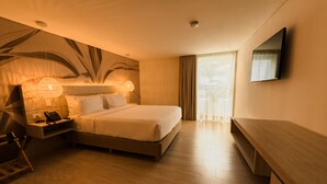 A modern hotel room with a large bed, bedside tables, a desk, and a flat-screen TV mounted on the wall. - Zafi Hotel (San Andrés)