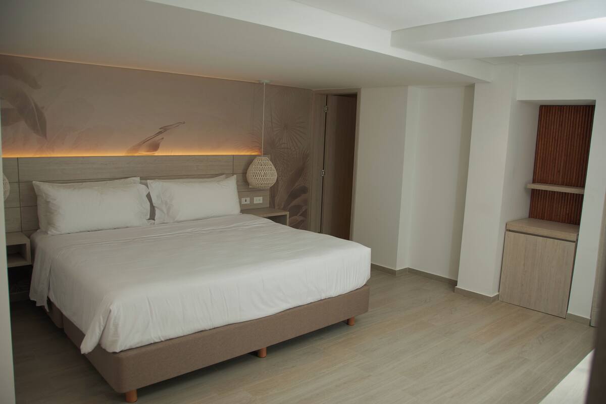 Un dormitorio moderno con una cama grande, una mesita de noche, una lámpara y un armario empotrado de madera.