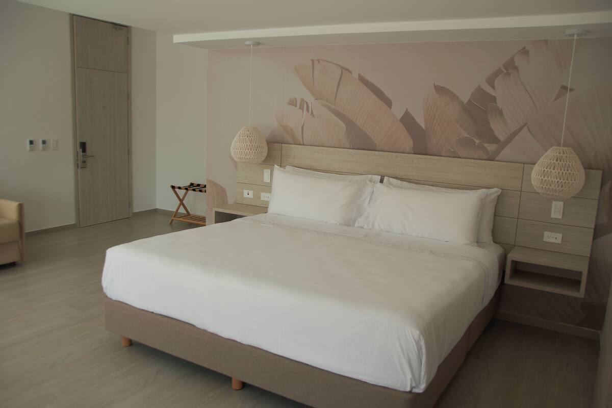 Una cama grande con sábanas blancas, un cabecero de madera y dos lámparas de noche.