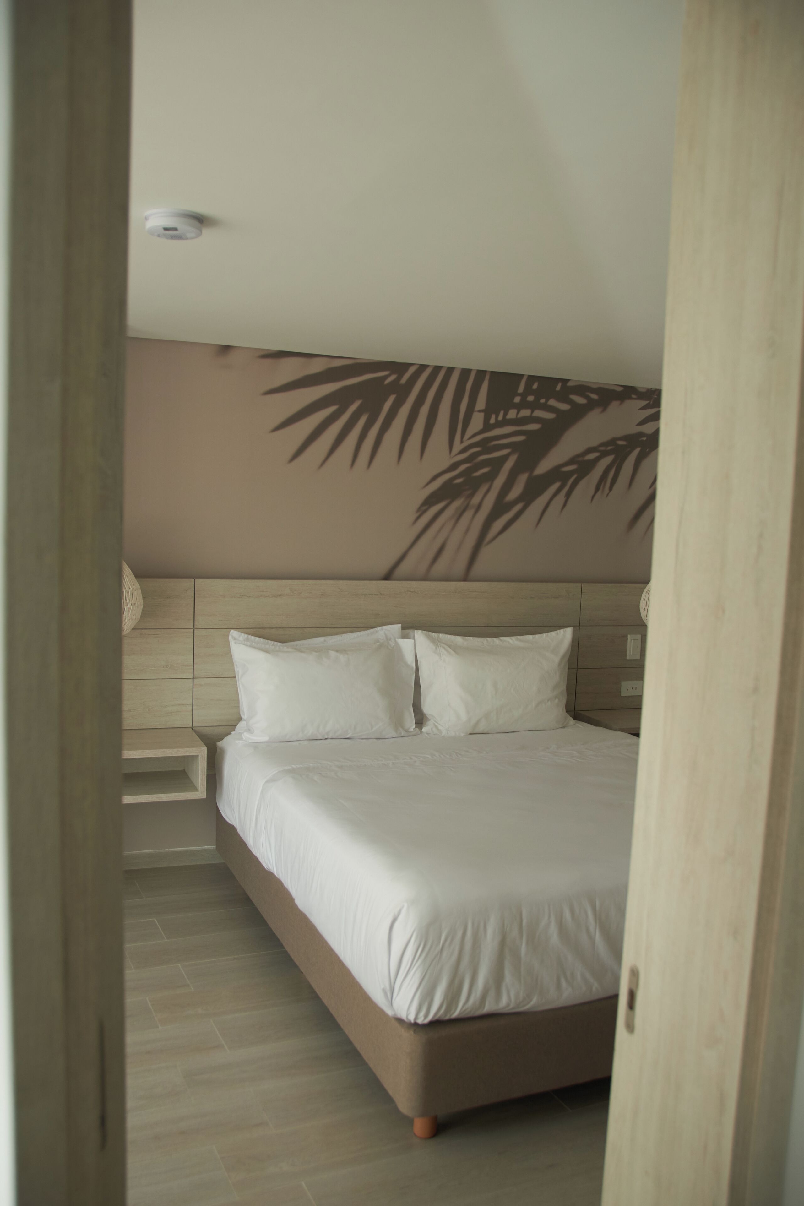 A bedroom with a bed, a headboard, and a wall-mounted light fixture.