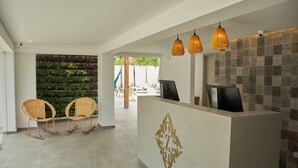 A reception area with a modern design, featuring a reception desk, two wicker rocking chairs, and a decorative wall with a geometric pattern. - Zafi Hotel (San Andrés)