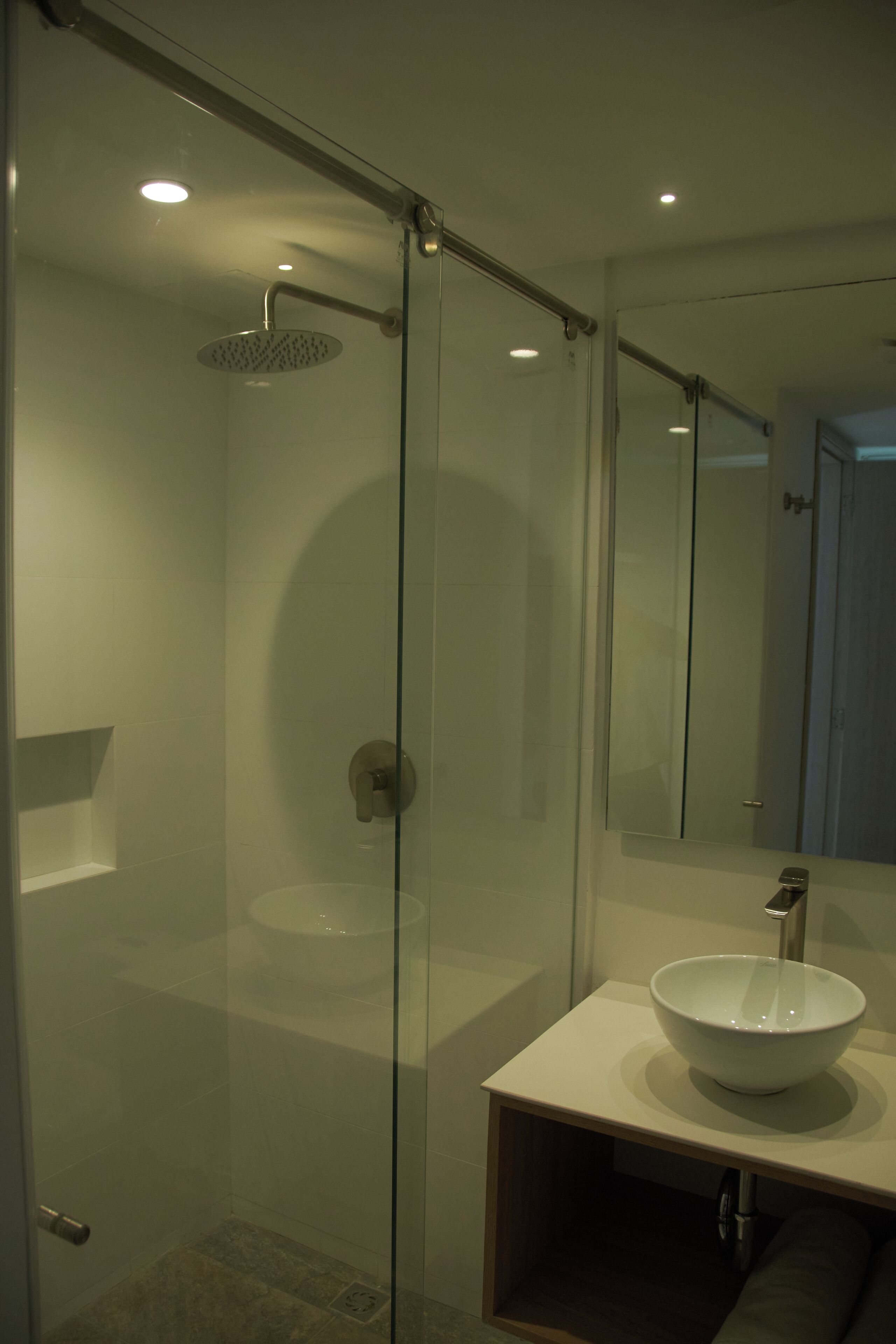 Une salle de bain moderne avec une douche à parois de verre, un lavabo blanc et un miroir.
