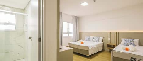 A hotel room with two beds, a shower, and a small desk.