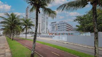 Una calle bordeada de palmeras y un edificio moderno con fachada de vidrio.