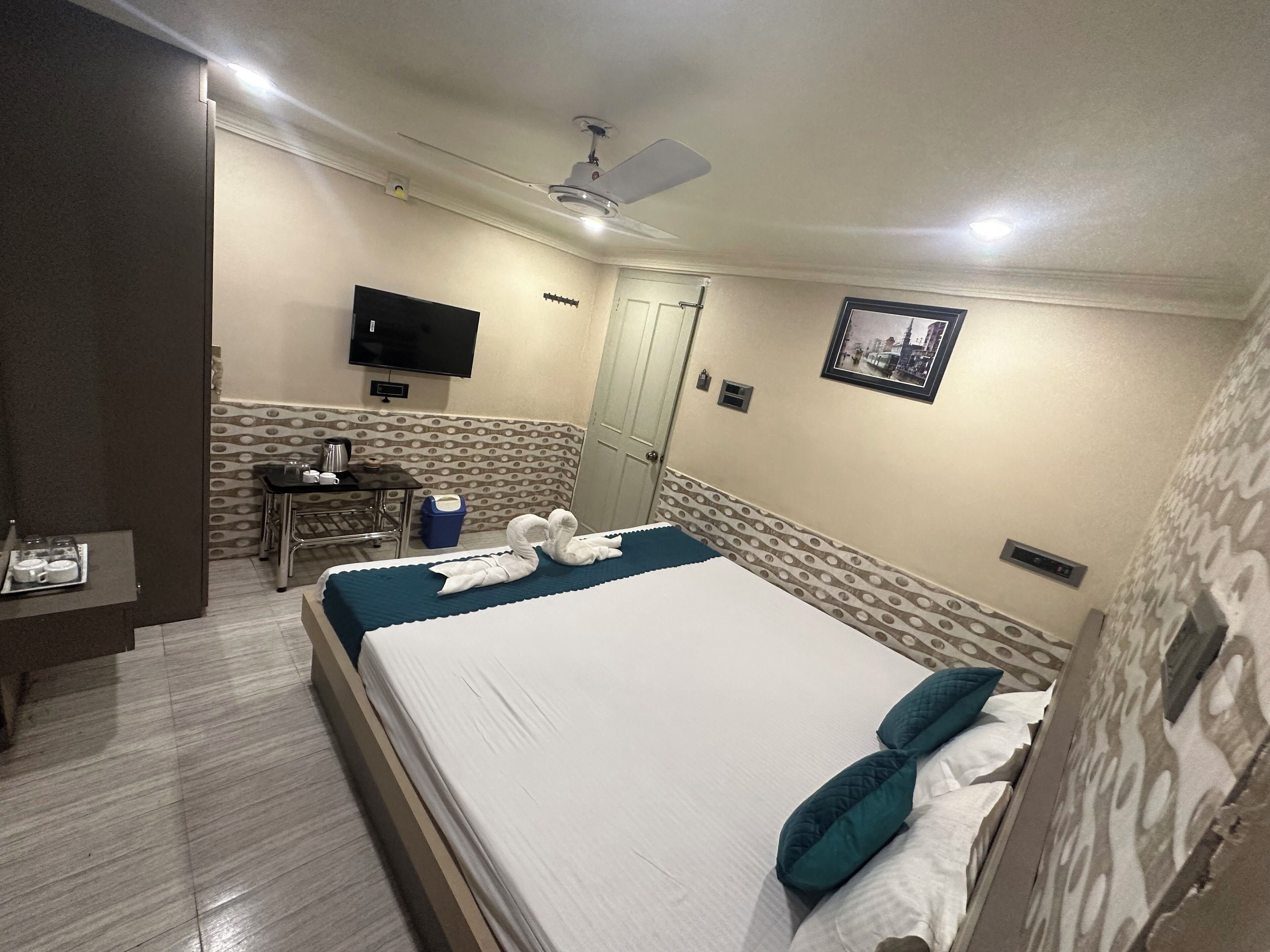 A hotel room with a bed, a desk, a chair, a television, and a picture on the wall.
