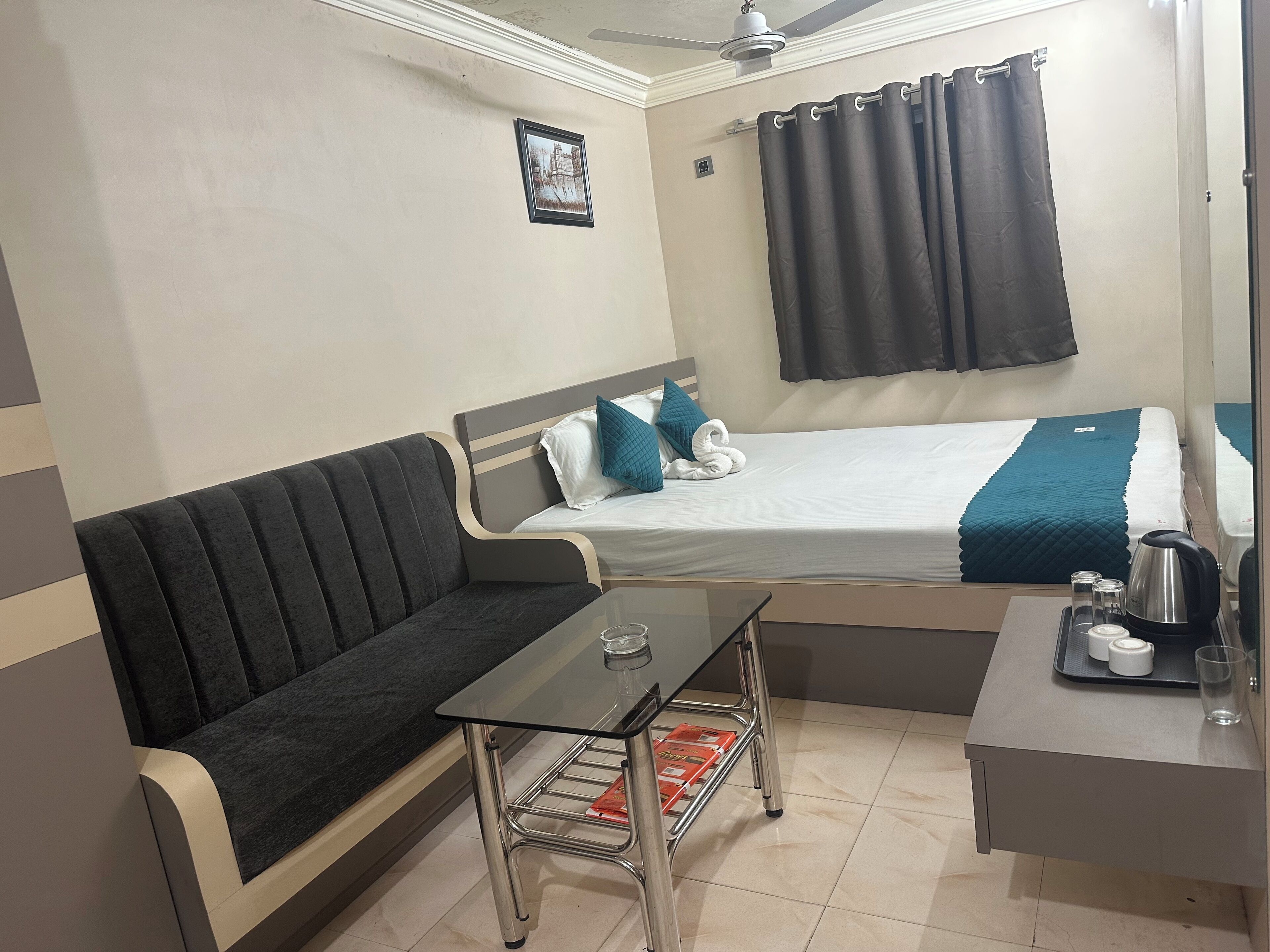 A hotel room with a bed, a sofa, a small table, and a desk.