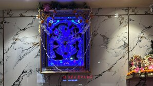 A reception desk with a marble wall backdrop and a framed decorative piece above it.