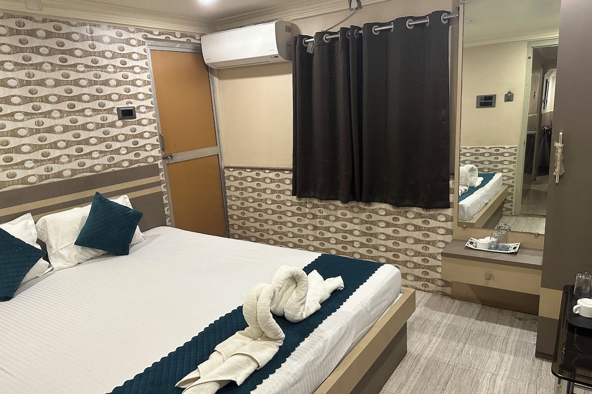 Habitación de hotel con cama, espejo de baño, toallero y aire acondicionado de pared.