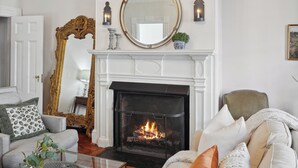 Un salon avec une cheminée, un lustre, un canapé et une table basse.