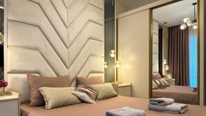 Un dormitorio moderno con una cama grande, una mesita de noche, un espejo y una pared con diseño geométrico.