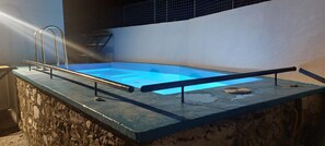 A rectangular swimming pool with a metal ladder on one side and a metal railing on the other. - The Pine Tree (Samos)