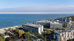 A coastal hotel with multiple buildings, a beach, and a view of the sea.