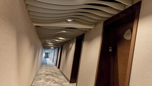 A hallway with a patterned carpet, wooden doors, and a ceiling with a wavy design.
