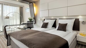 A modern hotel room with a large bed, a desk, and a chair.