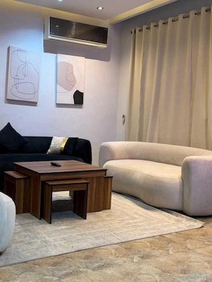 Una sala de estar con sofá, una mesa de centro y obras de arte en la pared.