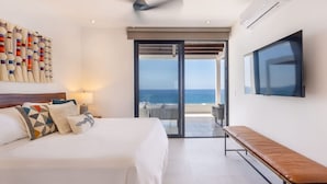 Une chambre d’hôtel moderne dotée d’un grand lit, d’une banquette, d’une télévision et d’un balcon offrant une vue sur la mer.