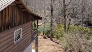 Une cabane en bois dotée d’un balcon, entourée d’arbres et située dans un paysage aride.